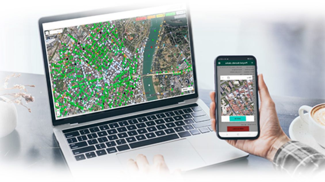 Laptop i pametni telefon prikazuju mapu grada sa zelenim i plavim oznakama koje predstavljaju lokacije sa kojih se vrši monitoring