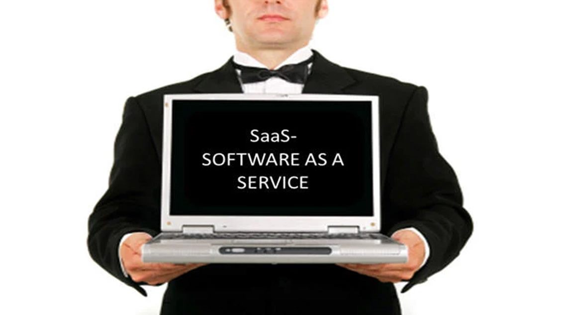 Slika na kojoj muškarac u smokingu u rukama drži otvoren laptop sa tekstom na monitoru: SaaS – SOFTWARE AS A SERVICE.