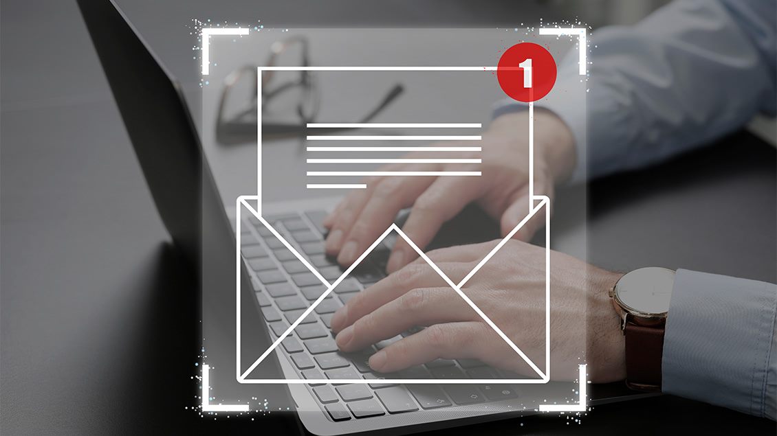 Ikona email poruke i obaveštenje o pristigloj poruci koje prekriva ruke osobe koja radi na laptopu.