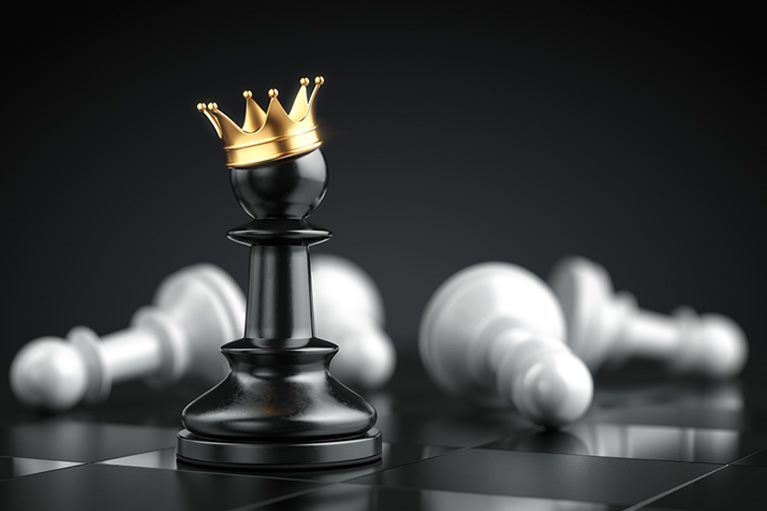 Crni šahovski pion sa zlatnom krunom među oborenim figurama – simbol uspeha i liderstva