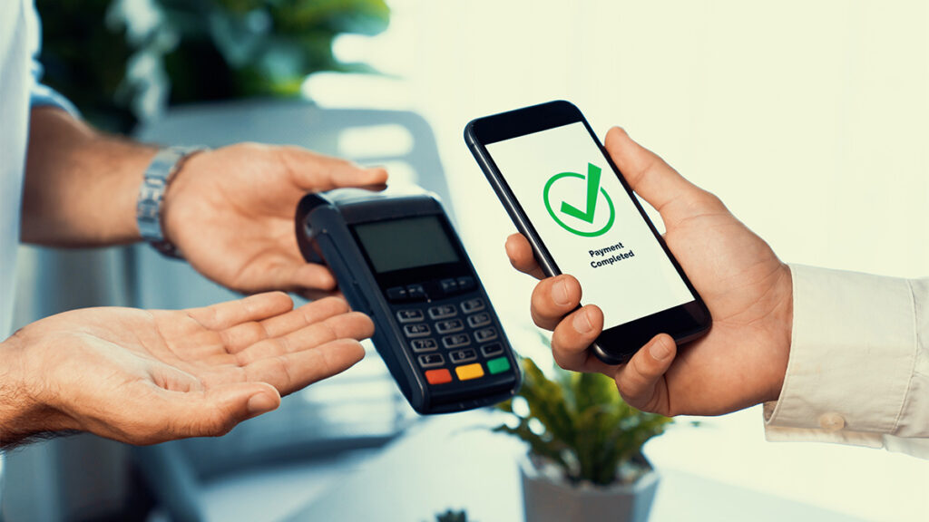 Osoba plaća mobilnim telefonom preko POS terminala.