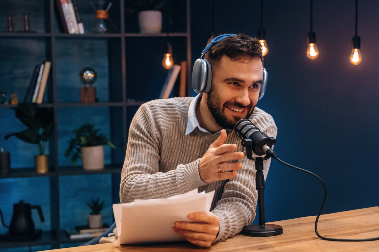 Voditelj snima video-podcast u studiju sa mikrofonom i slušalicama tokom razgovora.