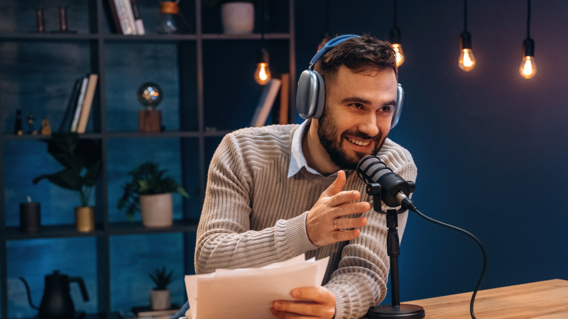 Voditelj snima video-podcast u studiju sa mikrofonom i slušalicama tokom razgovora.