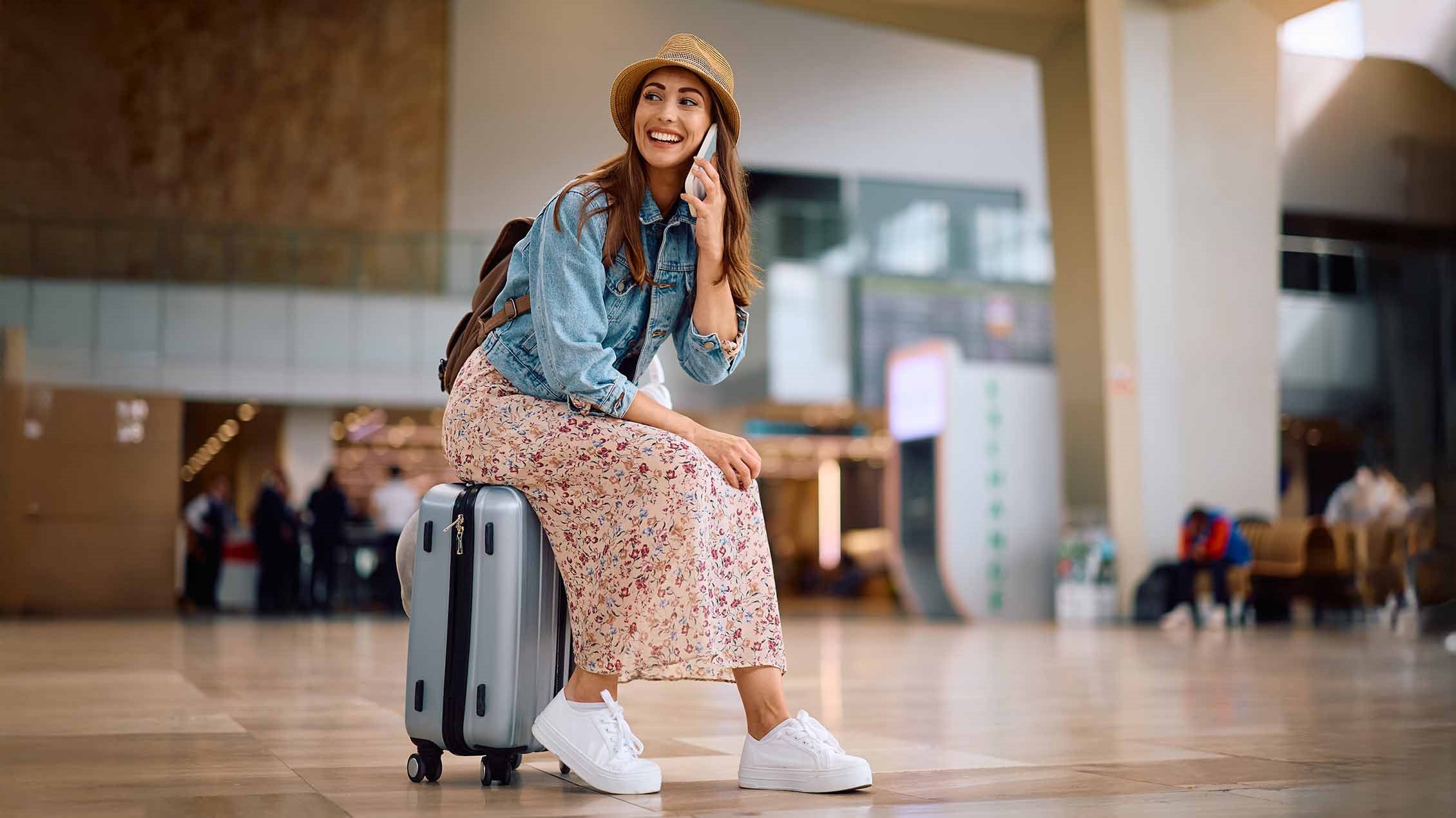 Putnica koristi mobilni telefon u inostranstvu na aerodromu, simbol rominga i korišćenja mobilnih usluga tokom putovanja.