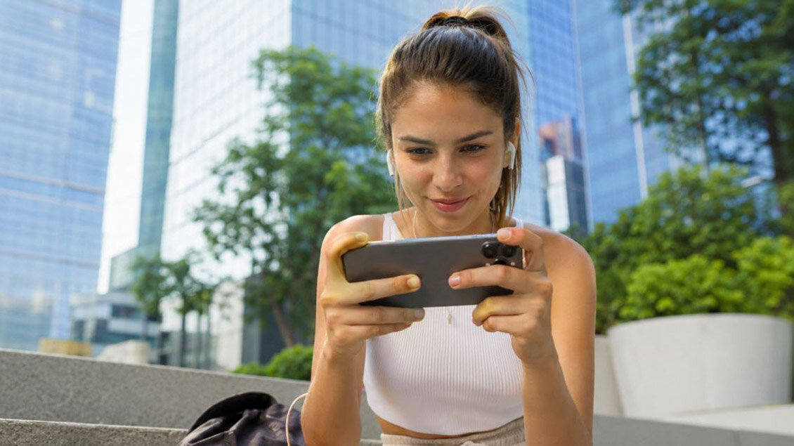 Devojka igra mobilnu igru na telefonu na otvorenom